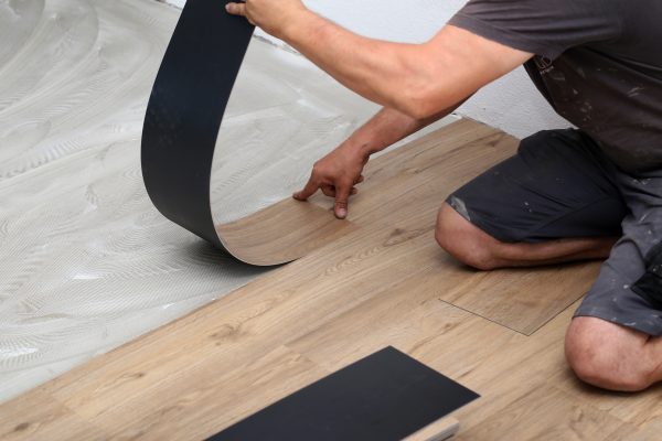 the worker installing new vinyl tile floor
